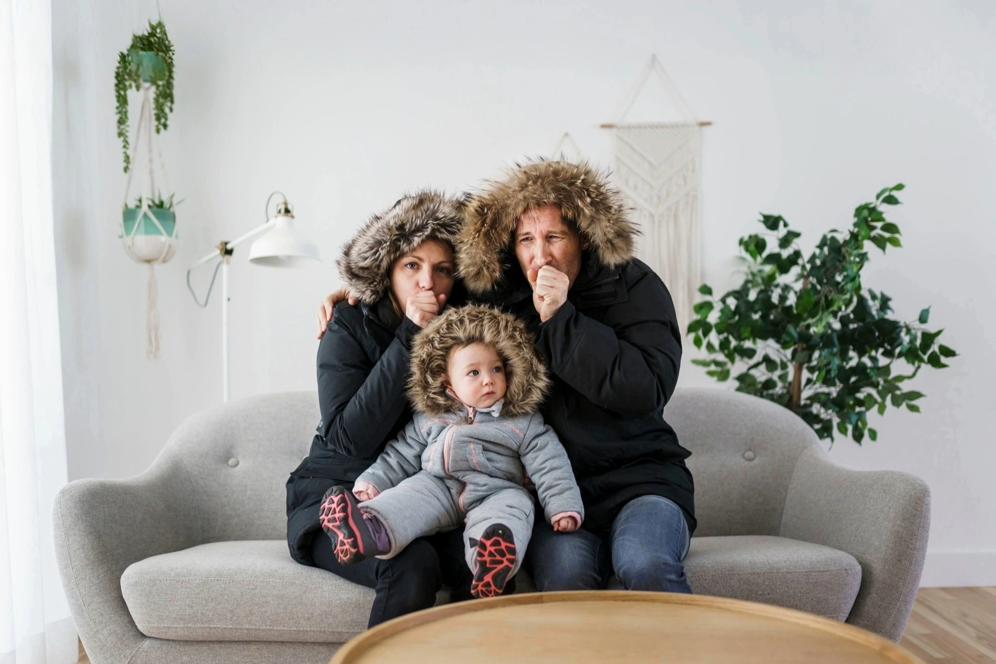 Family sitting indoors bundled in winter coats and hats because the heat is out 